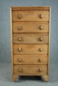 A mid century light oak tall chest, raised on later casters. H.129 W.61 D.41cm.