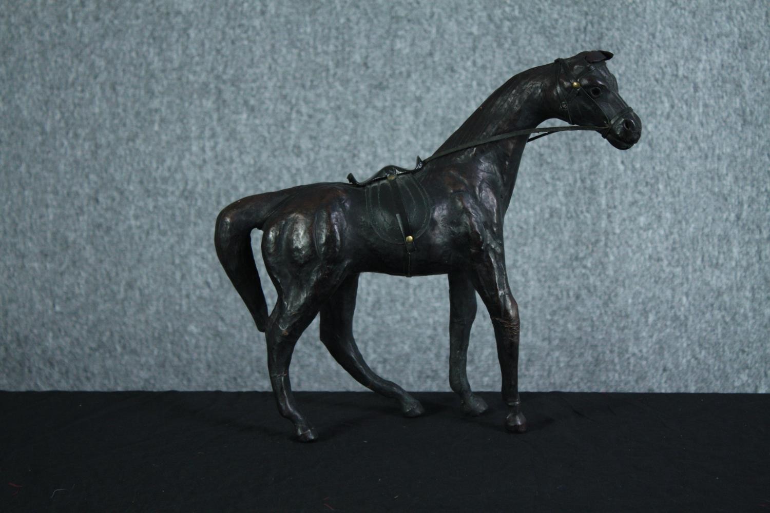 A well carved and detailed horse with leather bridle. Showing signs of past repairs. H.31 W.36 cm.