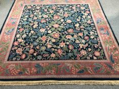 A hand woven carpet with a William Morris flowerhead design across the field within a