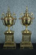 A pair of early 20th century brass and copper classical design twin handled urns on weighted