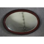 A wooden framed oval mirror. H.70 W.100 cm.