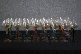 A large collection of stemmed coloured glasses. A mix of light blues, pinks, purple and reds. Mid