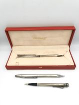 A collection of silver ballpoint pens and pencils, including a red leather cased S. T. Dupont silver