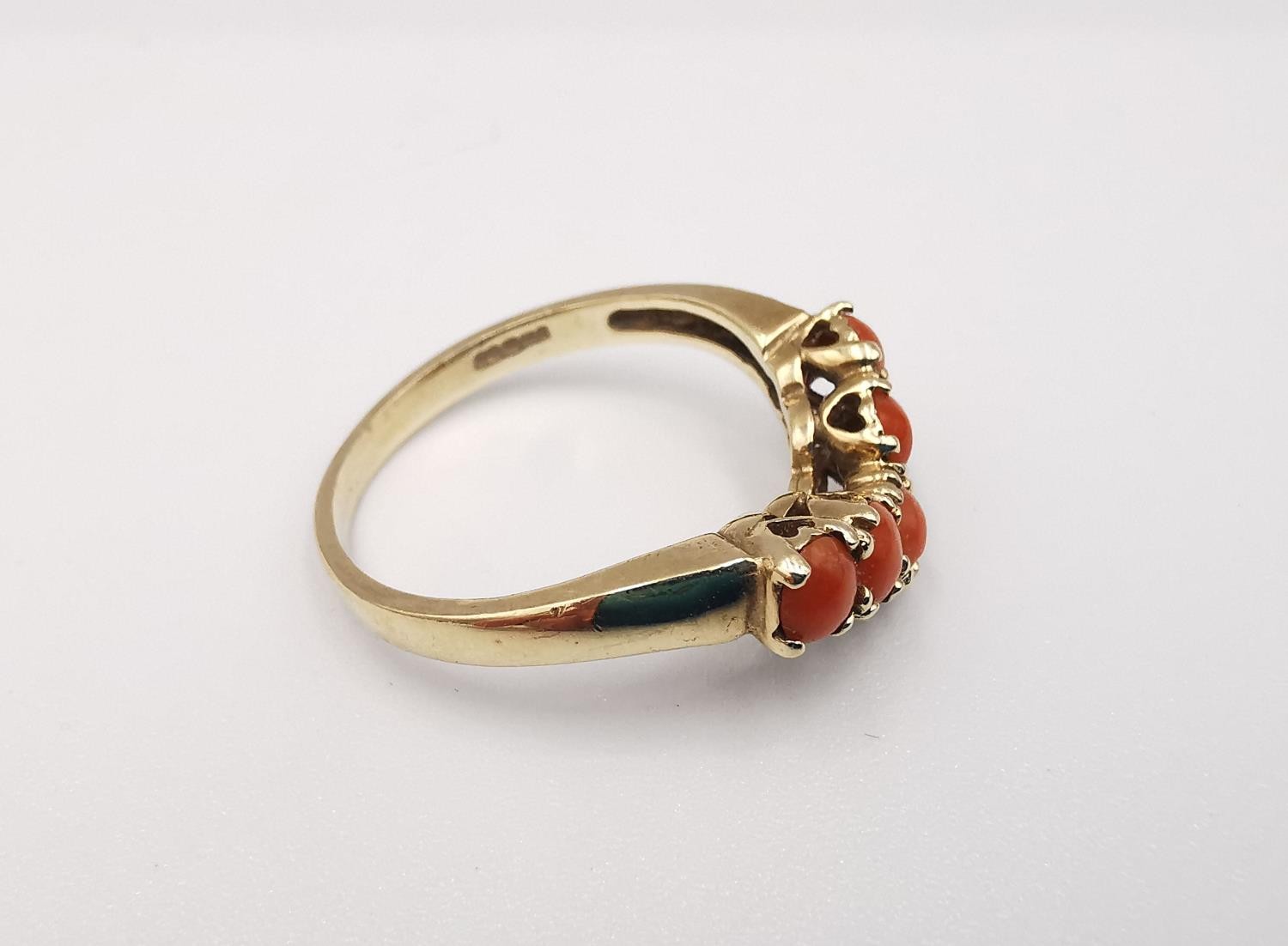A 9ct yellow gold coral V-shaped ring. Set with five round red coral cabochons in open back claw - Image 3 of 4