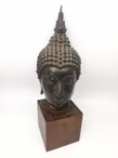 A 19th century Sukhothai style Thai bronze Buddha head on a wooden block stand. The head with serene