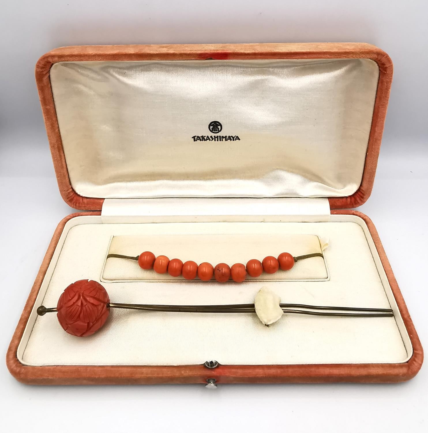 An orange velvet cased 1930s carved coral Bakelite floral design Kanzashi hair pin and string of