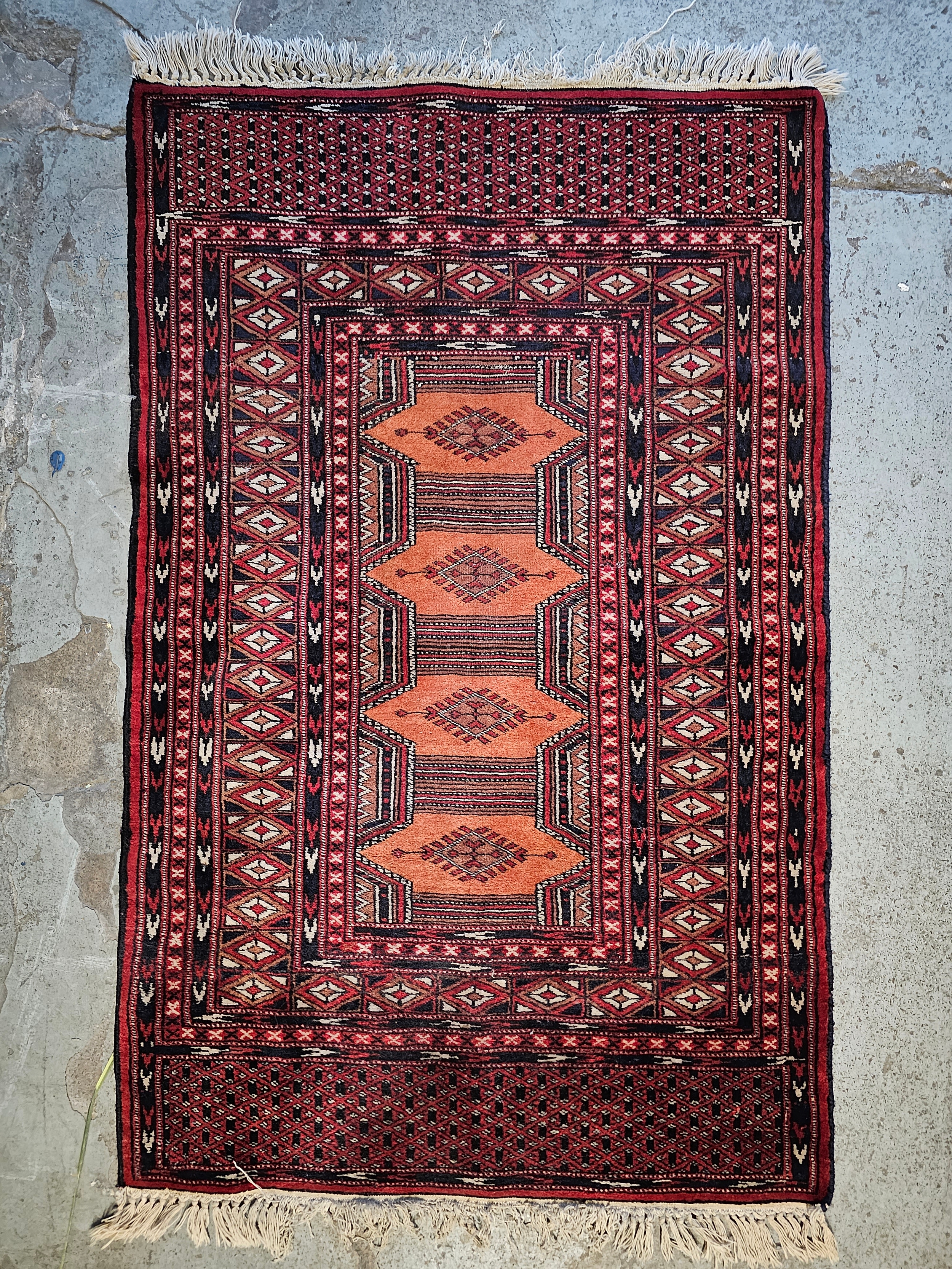 A small Eastern rug with repeating lozenge medallions on a madder field within multiple geometric