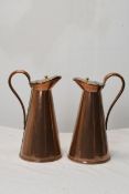 A pair of Arts and Crafts lidded copper water jugs. H.32