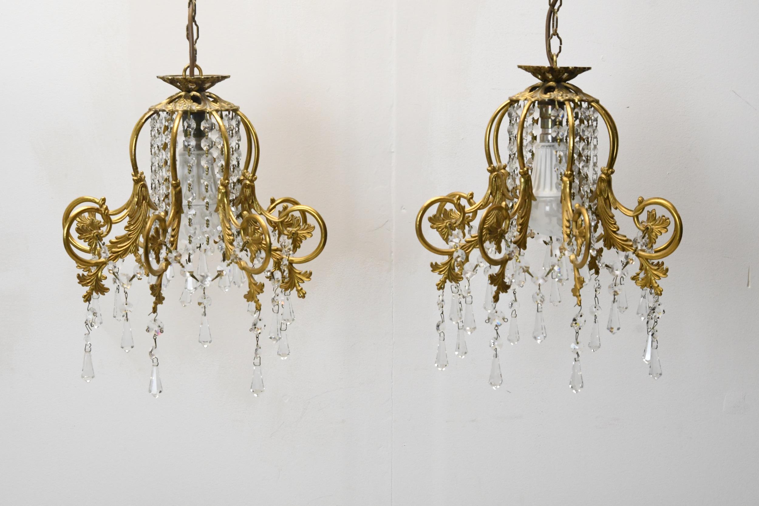A pair of hanging ceiling lights with scrolling gilt metal frames and crystal drops. H.62 W.30