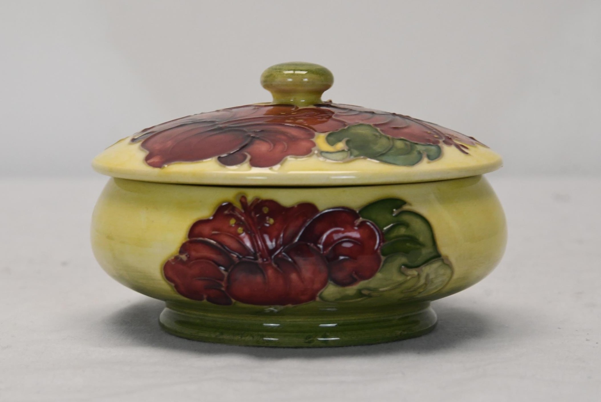 A Moorcroft Hibiscus lidded pot. H.8 W.12 D.12