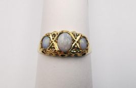 A Victorian 18ct yellow gold three stone opal and diamond ring. Set with three oval opal cabochons
