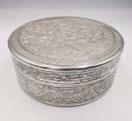 A circular engraved Egyptian silver box, all over decorated with a scrolling stylised foliate