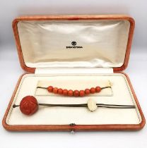 An orange velvet cased 1930s carved coral Bakelite floral design Kanzashi hair pin and string of