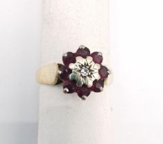 A pink metal (tests as 9ct) ruby and diamond cluster ring. Ring set to centre with a round eight cut