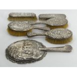 Three Victorian matching silver backed brushes, two others and an ornate silver hand mirror. UK