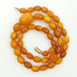 Butterscotch amber bead 57cm long necklace with a 9ct gold clasp, 35 grams. Largest bead 24mm