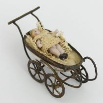 A miniature bisque porcelain doll in a pram, circa 1900. 65 x 30mm. UK Postage £12.
