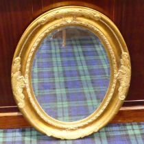 An ornate oval gilt framed mirror. 94 x 74 cm. Collection only