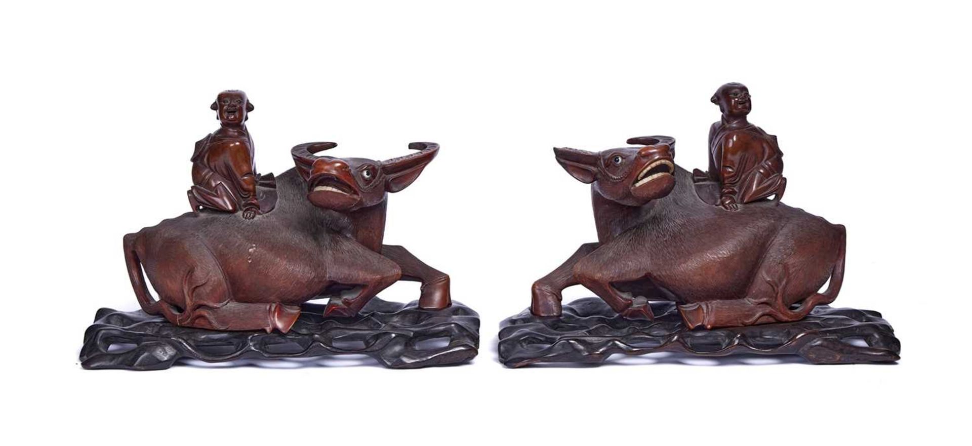 A PAIR OF QING DYNASTY CHINESE CARVED HARDWOOD GROUPS OF WATER BUFFALO WITH MEN