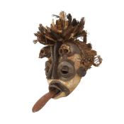 AN AFRICAN TRIBAL MASK MOUNTED WITH MONKEY SKULLS