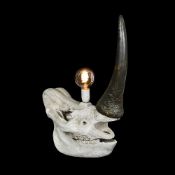 A FAUX RHINOCEROS SKULL MOUNTED AS A LAMP