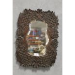 A CARVED WOODEN FRAMED BEVEL EDGED SHAPED WALL MIRROR