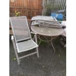 A METAL CIRCULAR PATIO TABLE WITH FOUR RECLINING CHAIRS