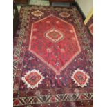 A LARGE EASTERN WOOLLEN RUG - MAINLY RED AND BLACK 305 X 203CM