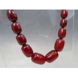 A VINTAGE CHERRY AMBER GRADUATED BEAD NECKLACE, single strand with screw barrel fastening, central