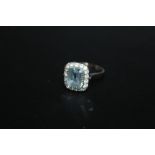 AN AQUAMARINE STYLE RING, stamped 750, centre stone untested, outer stones not diamonds, approx