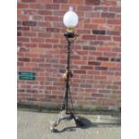 A WROUGHT IRON FLOOR STANDING OIL LAMP, having scrollwork decorations, hammered copper floral