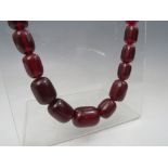 A VINTAGE CHERRY AMBER GRADUATED BEAD NECKLACE, single strand, no fastener, central bead W 2.5 cm,