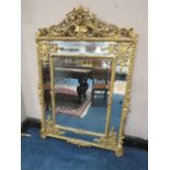 AN EARLY 19TH CENTURY GILT AND COMPOSITION WALL MIRROR, the scrolling Rococo style surmount above