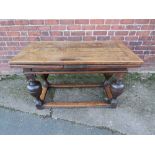 AN ANTIQUE OAK DRAWLEAF REFECTORY TABLE, raised on four baluster supports united by well-worn