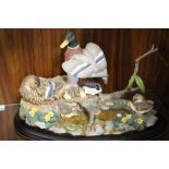 A LARGE AND HEAVY BORDER FINE ARTS STYLE TABLEAU OF DUCKS AND DUCKLINGS BY A POND