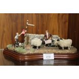 A BORDER FINE ARTS STYLE FIGURE TABLEAU OF A FARMER FEEDING SHEEP AND A BOY POSTING MAIL