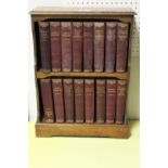 AN OAK TWO SHELF TABLE TOP BOOKCASE CONTAINING SIXTEEN VOLUMES OF CHARLES DICKENS NOVELS .