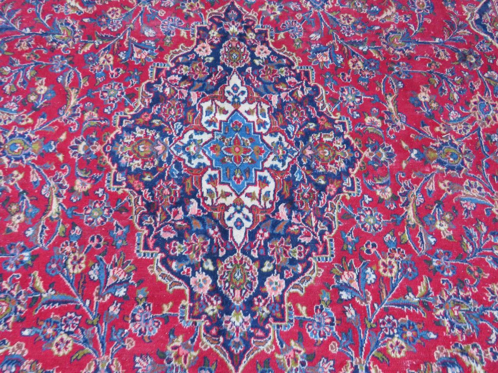 A LARGE RED / BLUE GROUND CARPET, APPROX 389 X 297 CM - WEAR THROUGHOUT