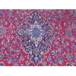 A LARGE RED / BLUE GROUND CARPET, APPROX 389 X 297 CM - WEAR THROUGHOUT