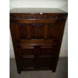 AN OAK REPRODUCTION DRINKS CABINET WITH LINEN FOLD DESIGN