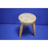 A MILKING TYPE STOOL WITH CELTIC DECORATION TO THE TOP