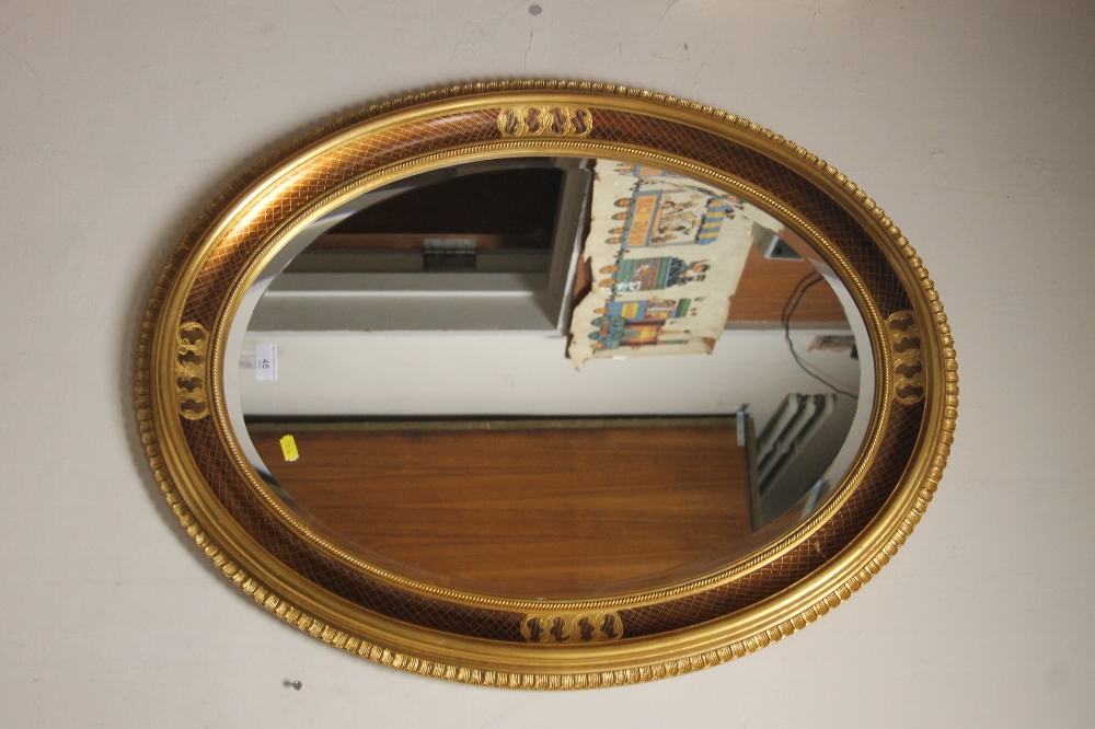 A LARGE OVAL BEVEL EDGED MODERN MIRROR SIZE 85 CM X 65 CM