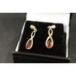 A PAIR OF UNMARKED YELLOW METAL DROPPER EARRINGS SET WITH GARNET TYPE TEARDROP STONES