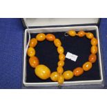 A STRING OF ANTIQUE BUTTERSCOTCH AMBER BEADS, LARGE CENTRAL BEAD ABOUT 3 CM LONG, OVERALL LENGTH