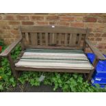 A WOODEN GARDEN BENCH WITH STRIPED PADDED SEAT