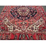 A LARGE RED GROUND PATTERNED WOOLLEN CARPET APPROX 296 X 220 CM