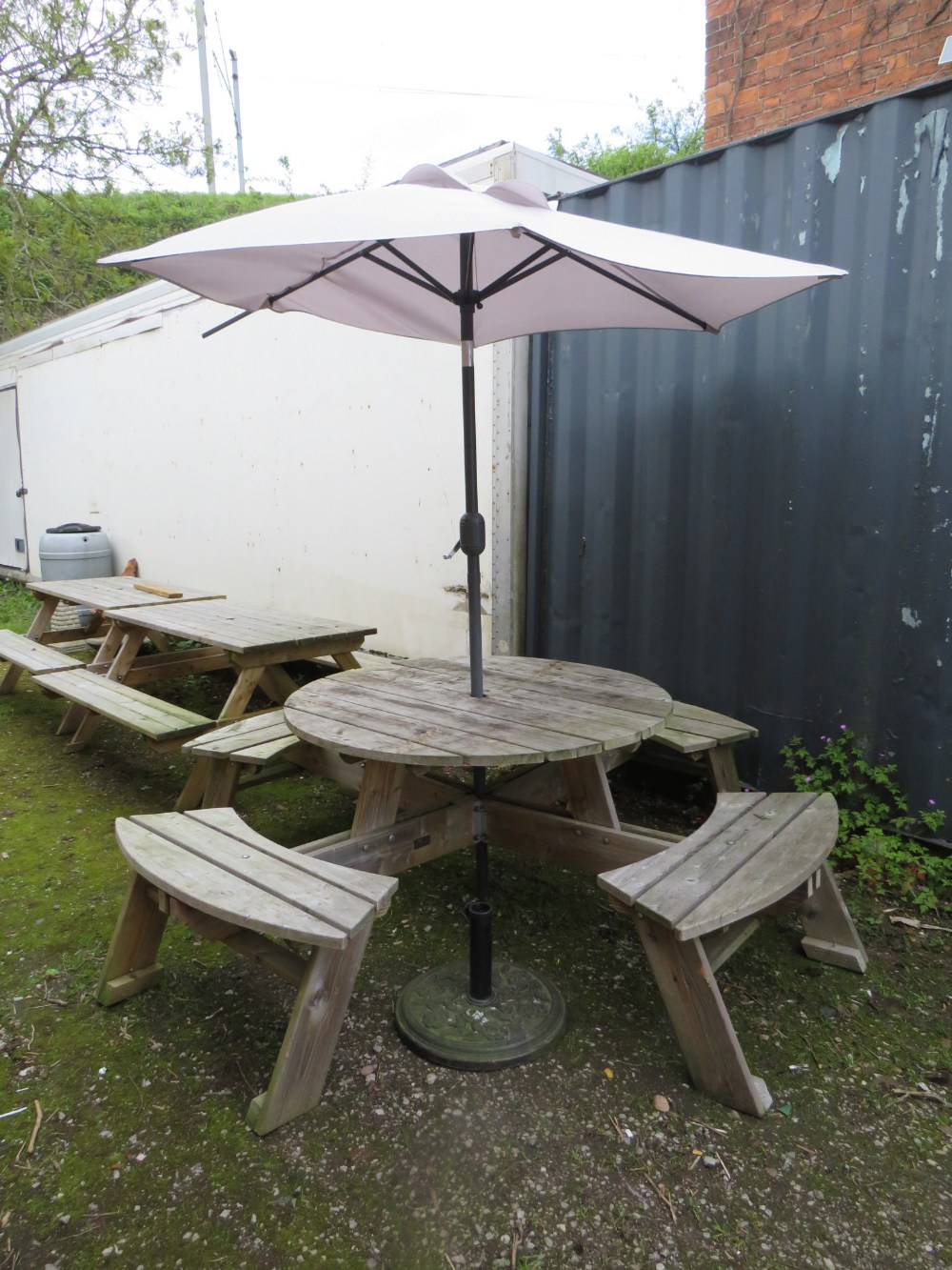 A CIRCULAR WOODEN GARDEN / PATIO TABLE WITH PARASOL AND STAND