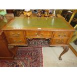 AN EARLY 20TH CENTURY MAHOGANY CARVED LEATHER TOPPED WRITING DESK WITH FIVE DRAWERS, RAISED ON