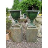 A PAIR OF GREEN PAINTED CAST LOBED URNS, H 52 cm, raised on two sandstone bases, Overall H 106 cm (