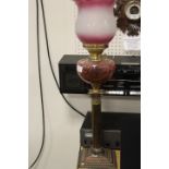A TWIN DUPLEX BURNER VINTAGE OIL LAMP WITH CRANBERRY STYLE RESERVOIR AND DECORATIVE SHADE